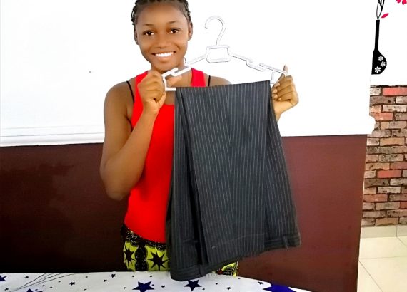 A photo of a lady showing how to hang a pair of trousers after ironing