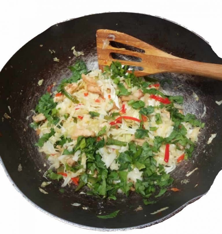 fried cabbage in a sauce pan and a wooden spatula